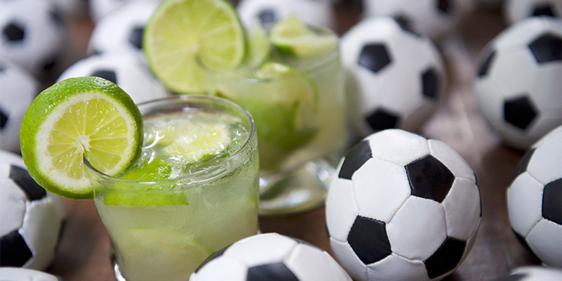 bebidas geladas em cima de uma mesa cheia de bolinhas de futebol